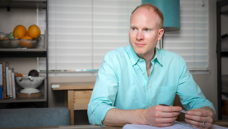 Julian Bradley sitting with pen and sheet music